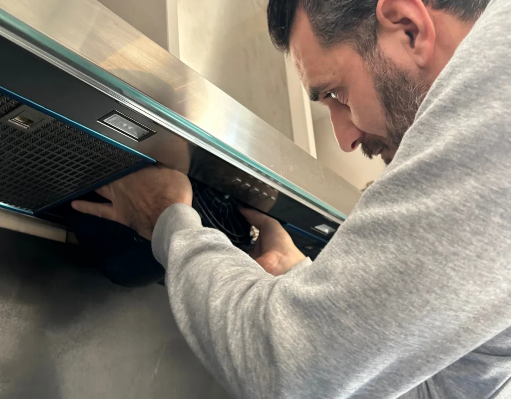 Technicien intervenant sur une hotte aspirante directement chez le consommateur.